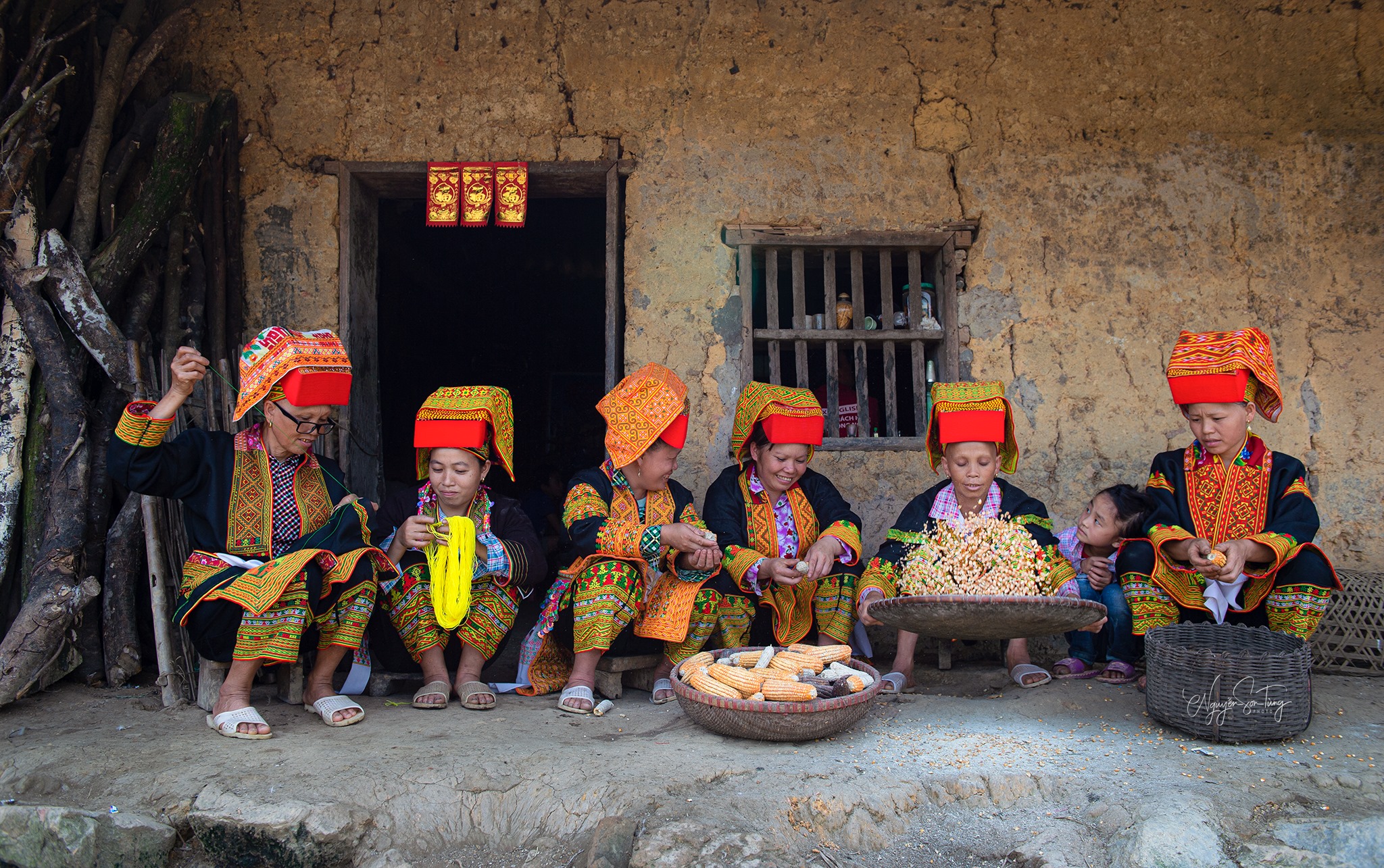 Phụ nữ sàng ngô trước hiên nhà