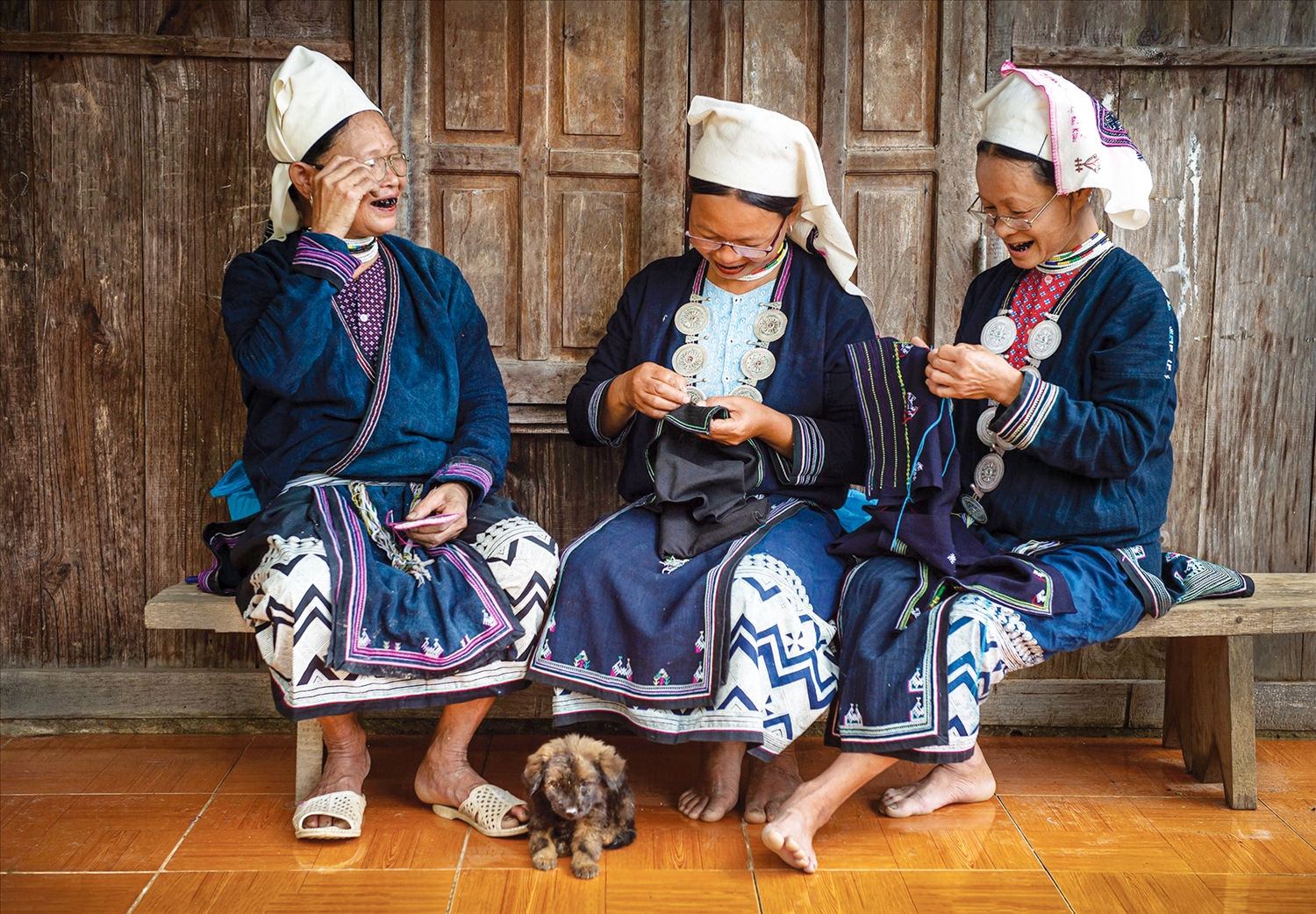 Phụ nữ Dao Tiền bên khung thêu trước hiên nhà.