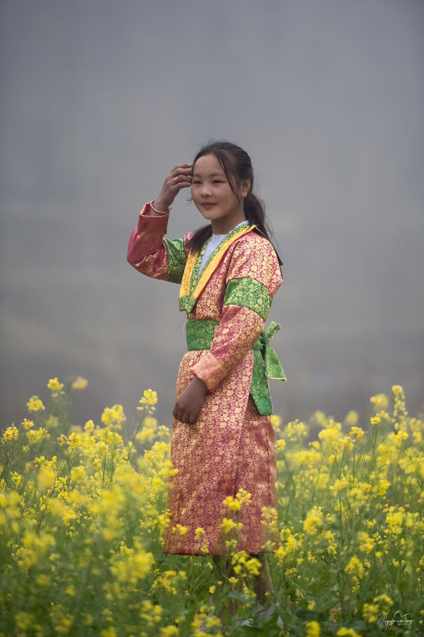 Thiếu nữ áo thổ cẩm đứng giữa ruộng hoa cải vàng
