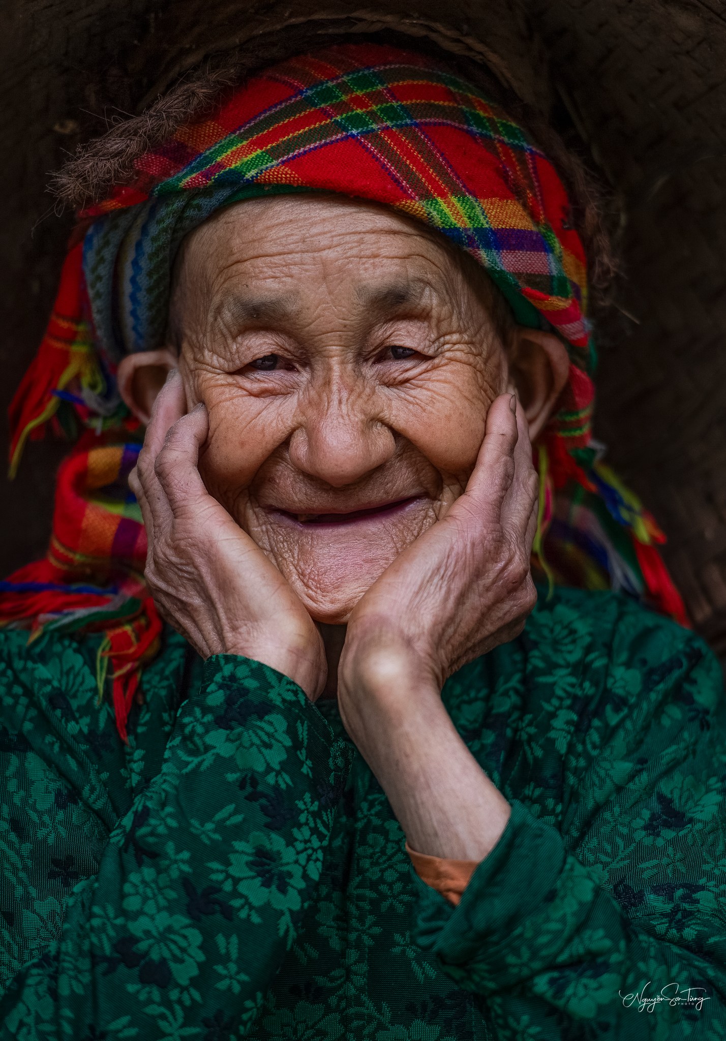 Cụ bà khăn thổ cẩm cười, hai tay ôm má