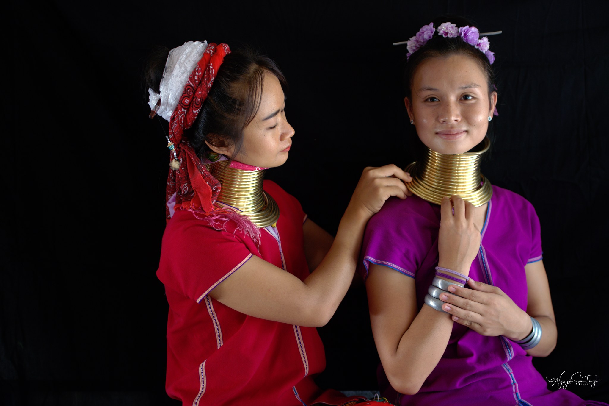 Bàn tay khẽ chỉnh lại bộ vòng cho nhau — một cử chỉ thân thuộc trong làng