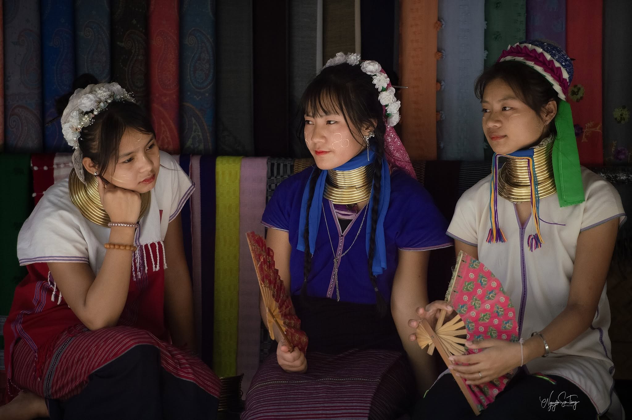 Giữa những tấm vải sặc sỡ của làng — ba cô gái và những chiếc quạt hoa