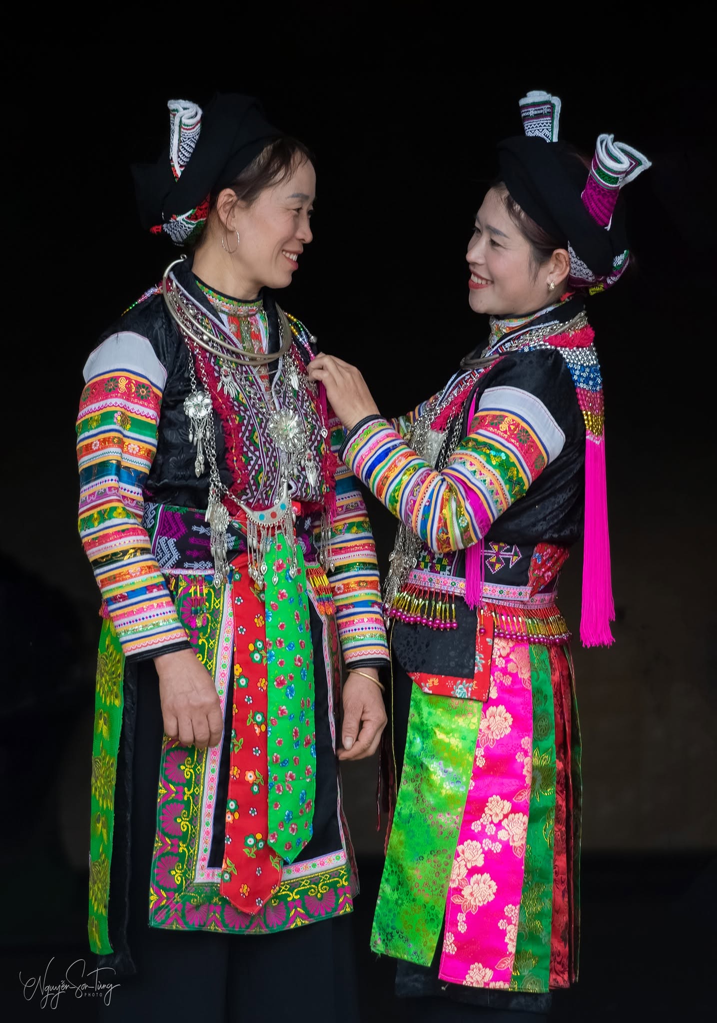 Hai phụ nữ Dao đỏ chỉnh vòng bạc cho nhau