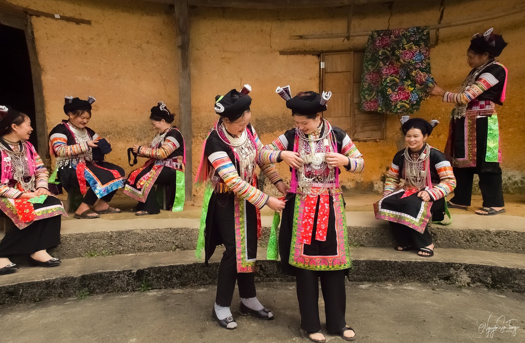 Nhóm chị em Dao đỏ chỉnh trang phục cho nhau giữa sân